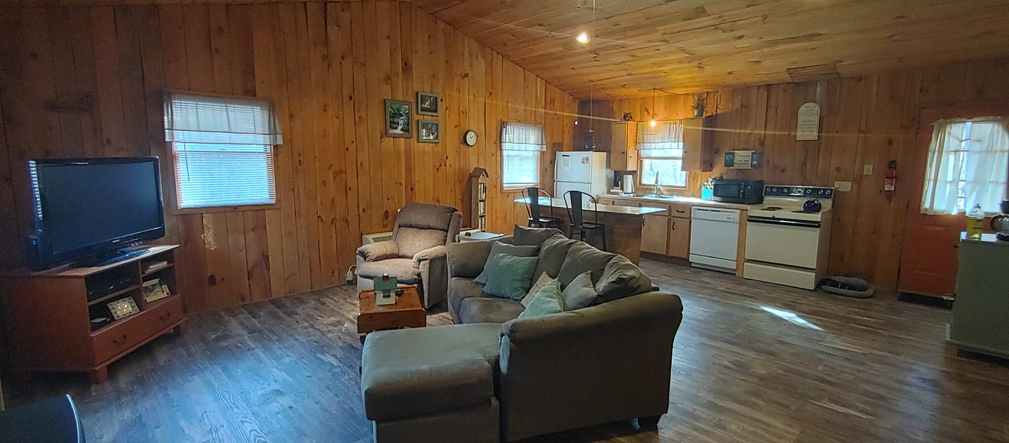 Photo 625_12513.jpg - The Nest is knotty pine on walls and ceiling.  The living room, dining and kitchen all flow together.  It really is a large, open living area for a two person cabin.  Couch and recliner.  Very comfortable.  Gas fireplace and cable TV and Wifi!  All set!